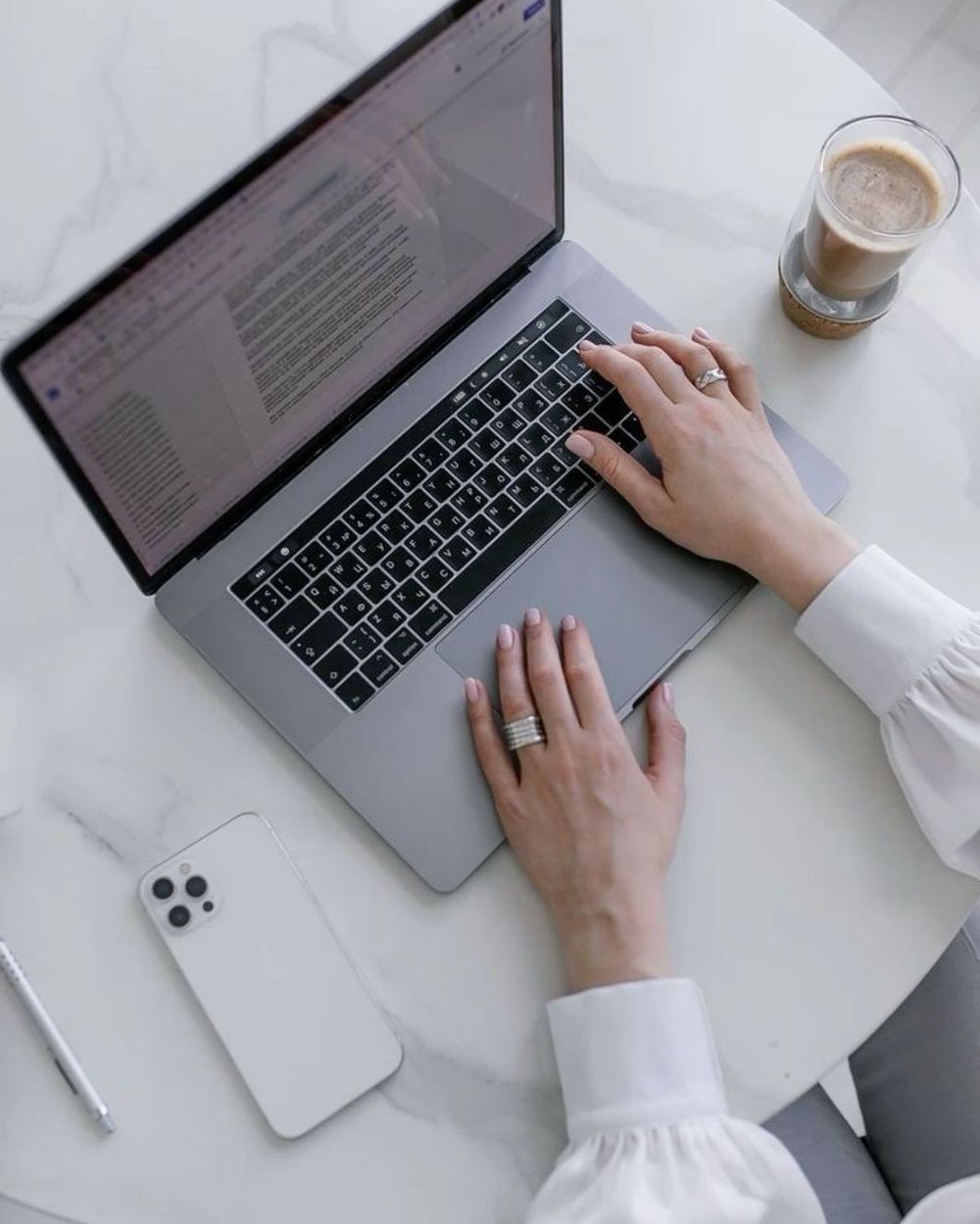Working on a laptop at a marble desk with coffee and a phone